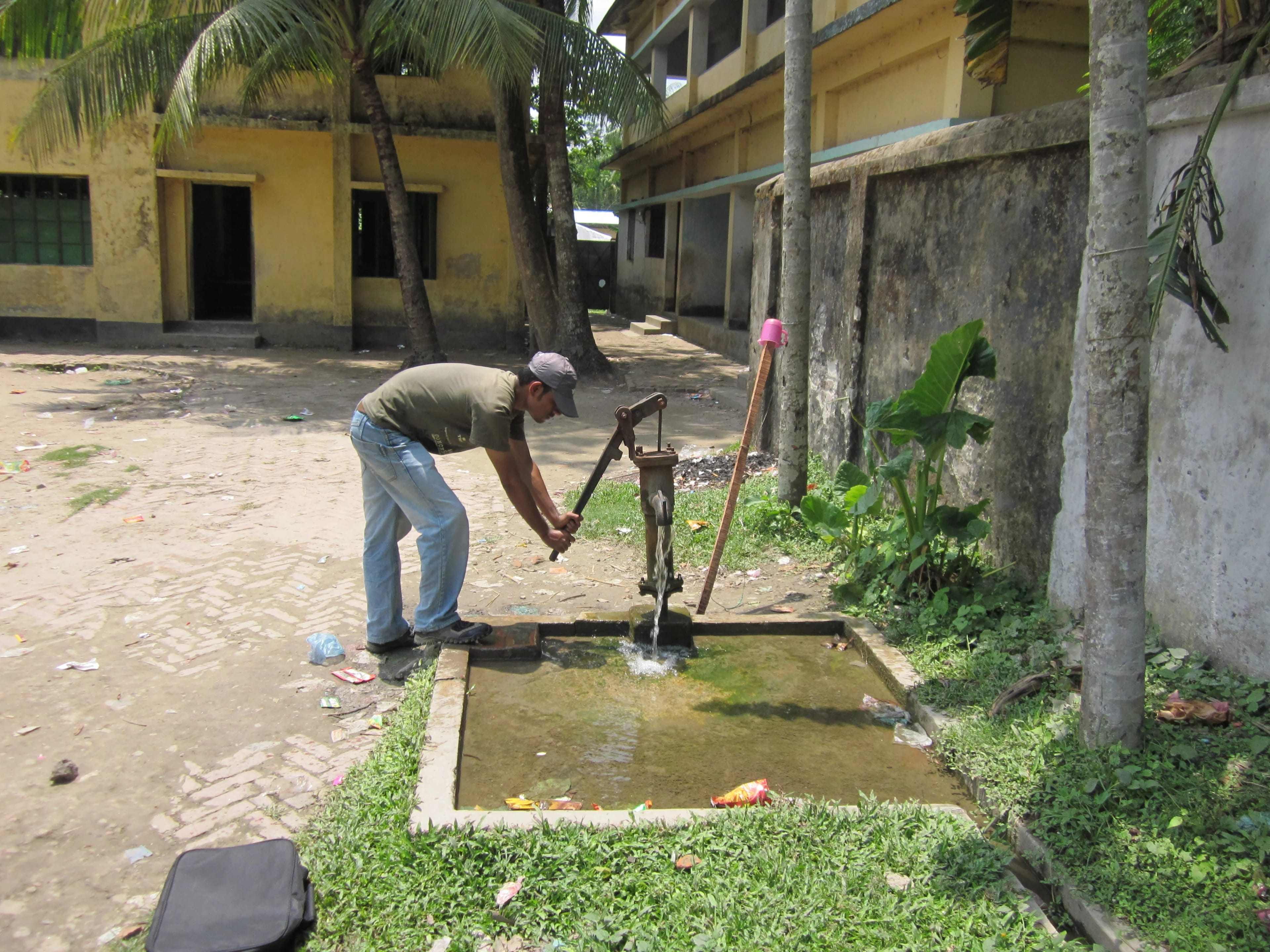 A man pumping a hand-pump tubewell in Bangladesh